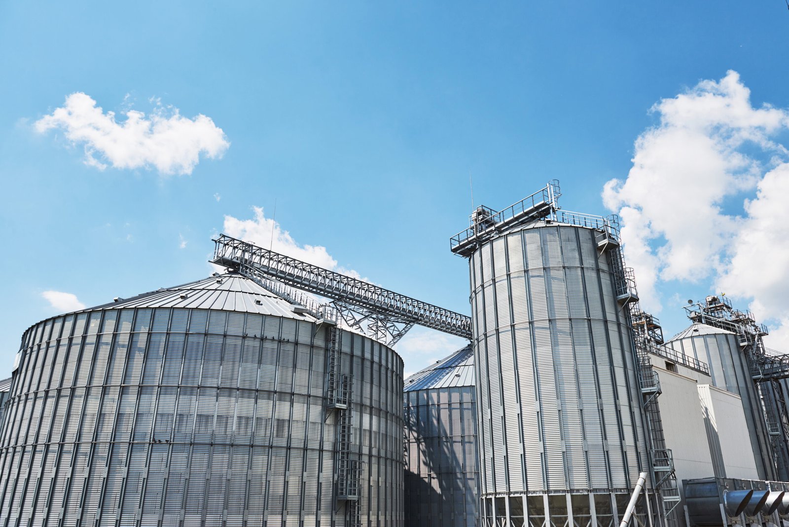 agricultural silos. building exterior. storage and drying of grains, wheat, corn, soy, sunflower against the blue sky with white clouds